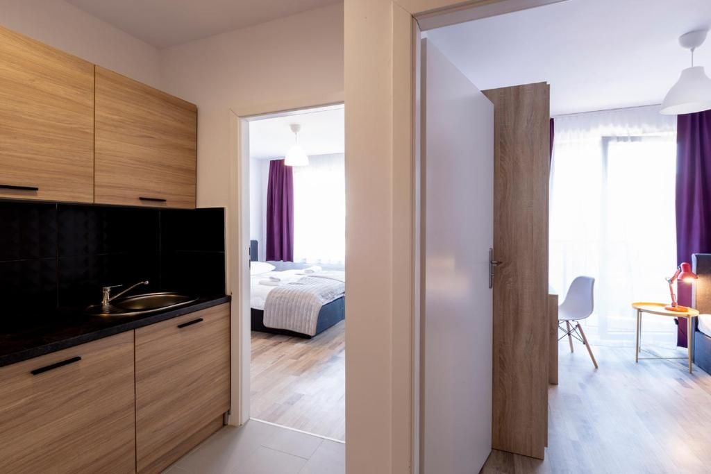 Una habitación de hotel moderna con cocina, una cama y un área de descanso con mesa y silla.