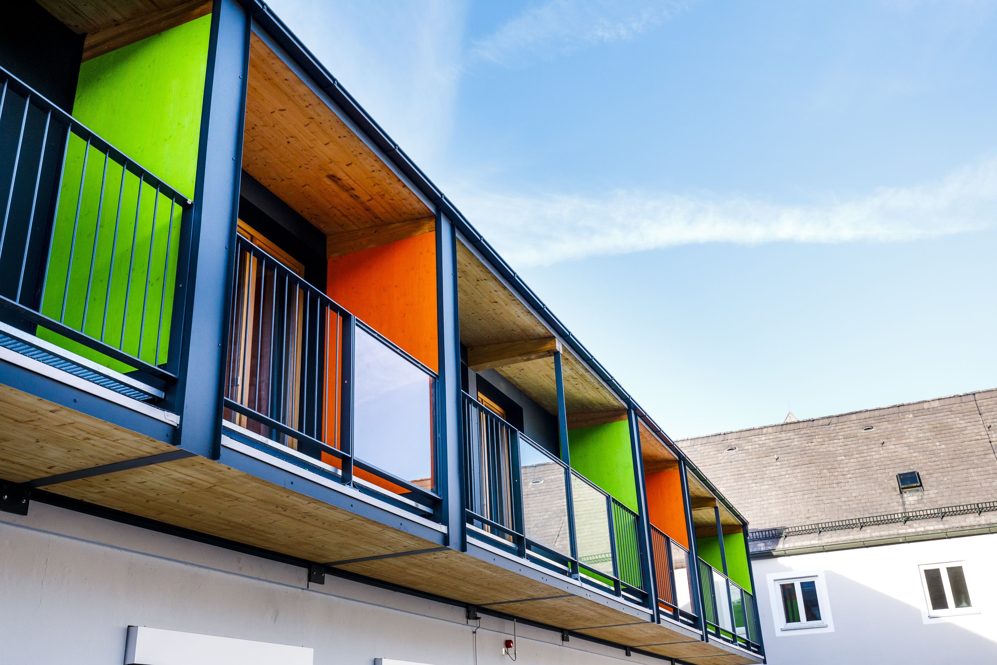 Un immeuble à plusieurs étages doté de balcons avec des garde-corps en bois et des panneaux de couleurs vives.