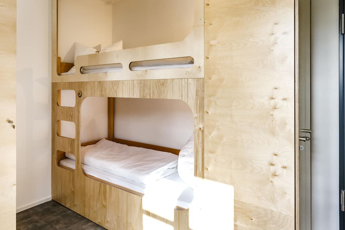 Une chambre avec un lit superposé au design en bois, un petit bureau et une porte.