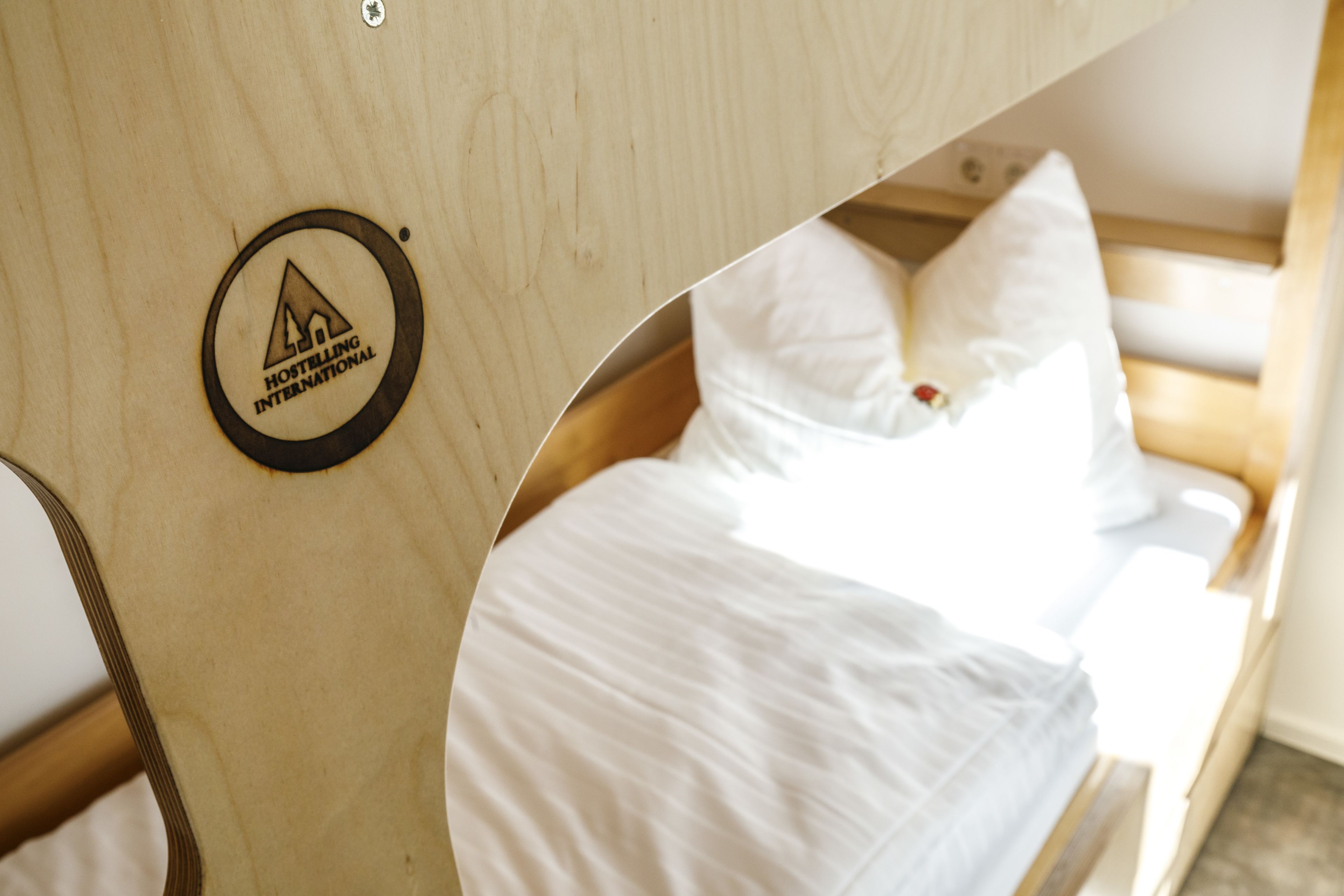 A wooden bunk bed with a logo for Hostelling International.