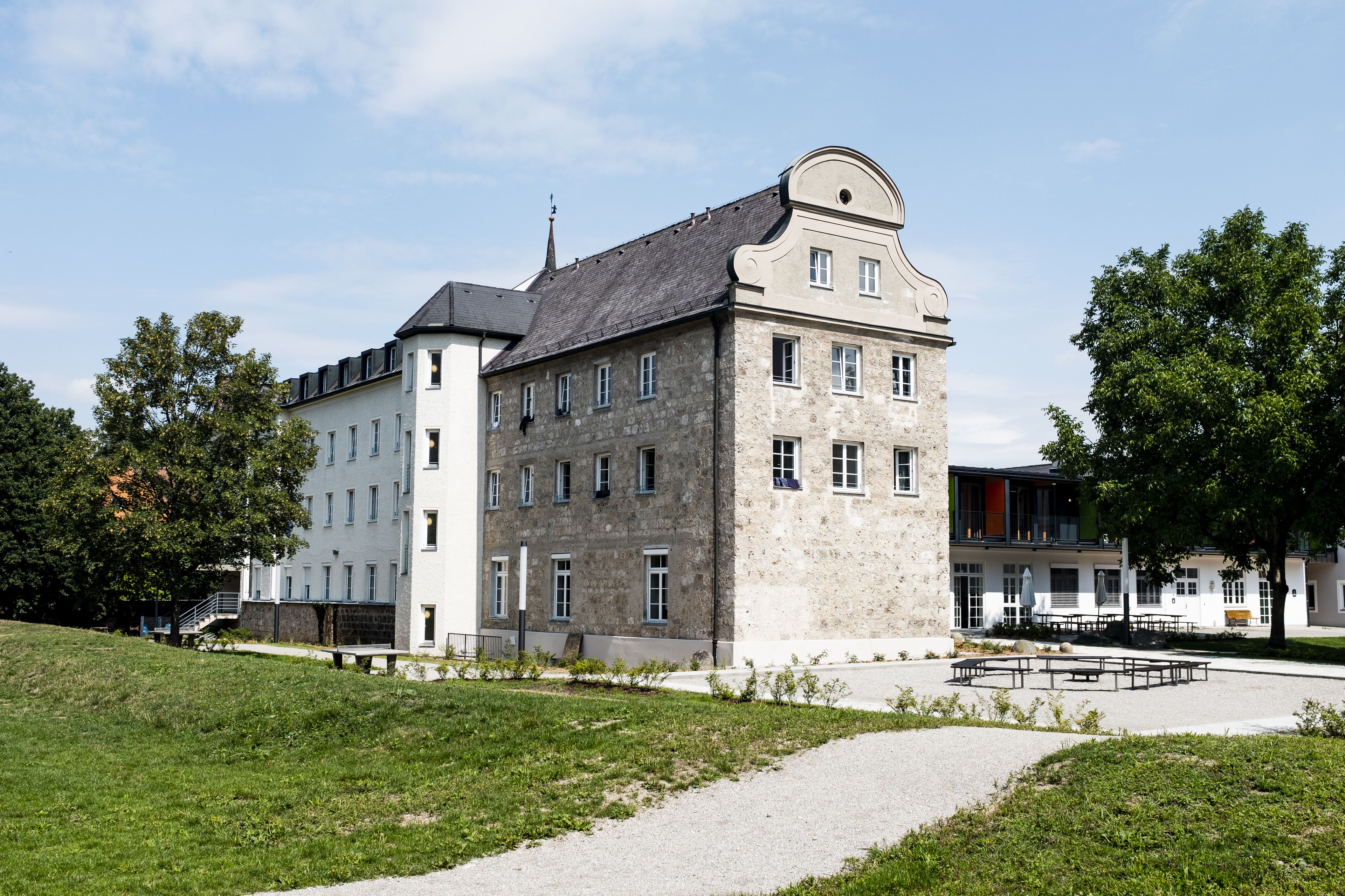 A historic building with a stone facade, multiple windows, and a central entrance.