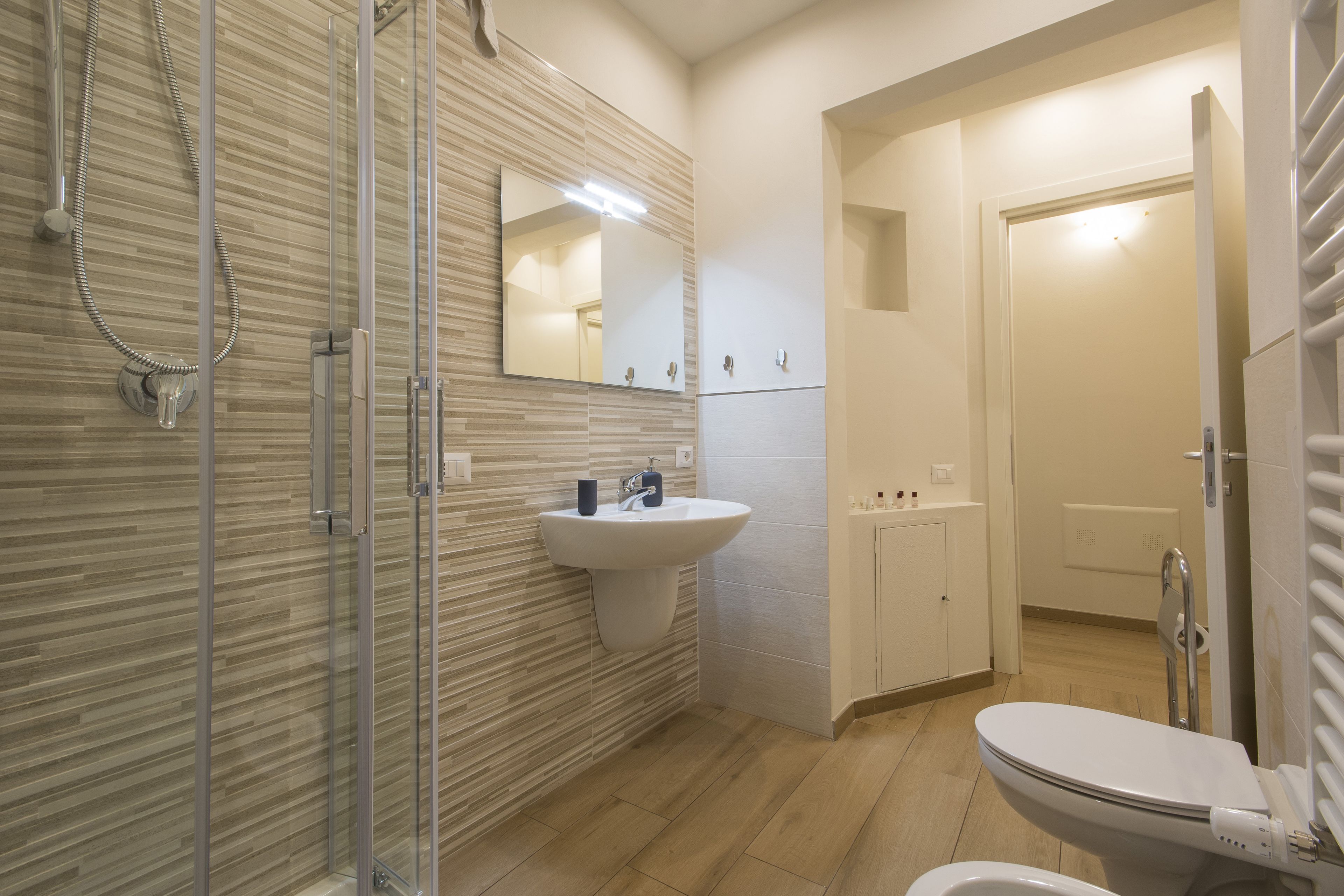 A modern bathroom with a glass shower enclosure, a white sink, and a toilet.