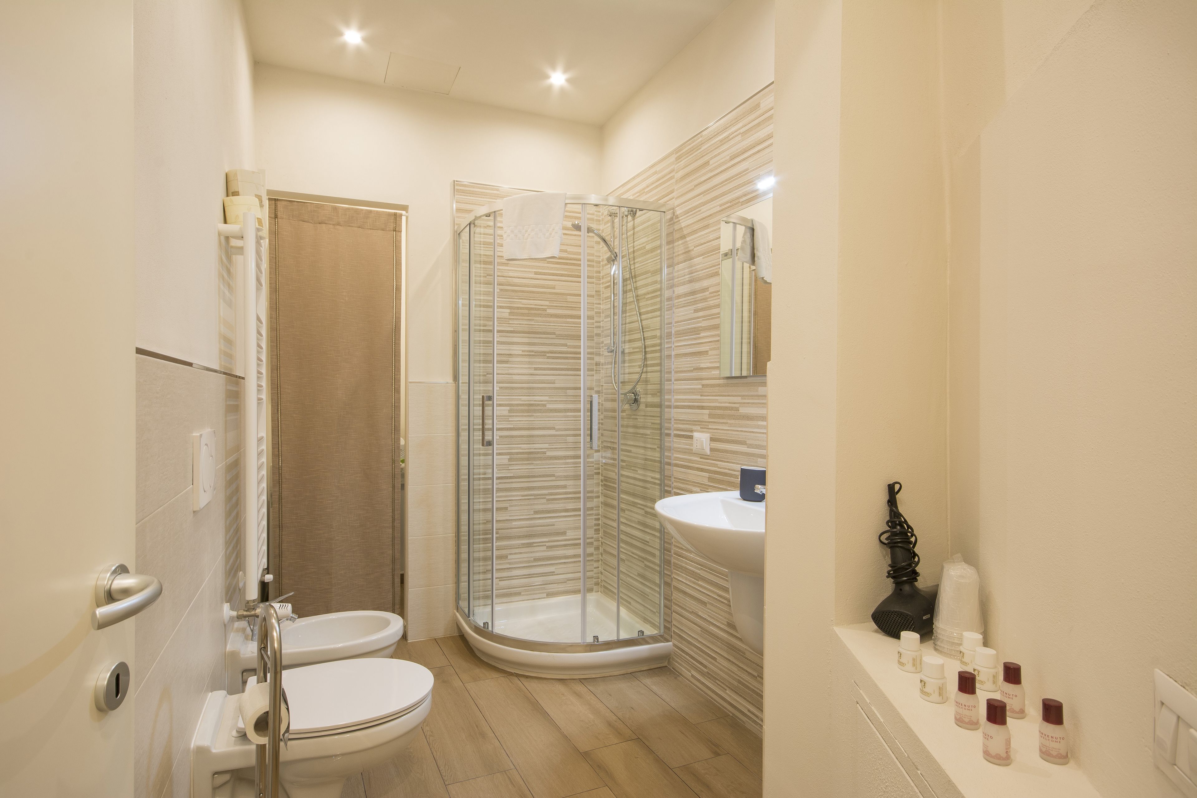 A modern bathroom with a glass-enclosed shower, a toilet, and a sink.