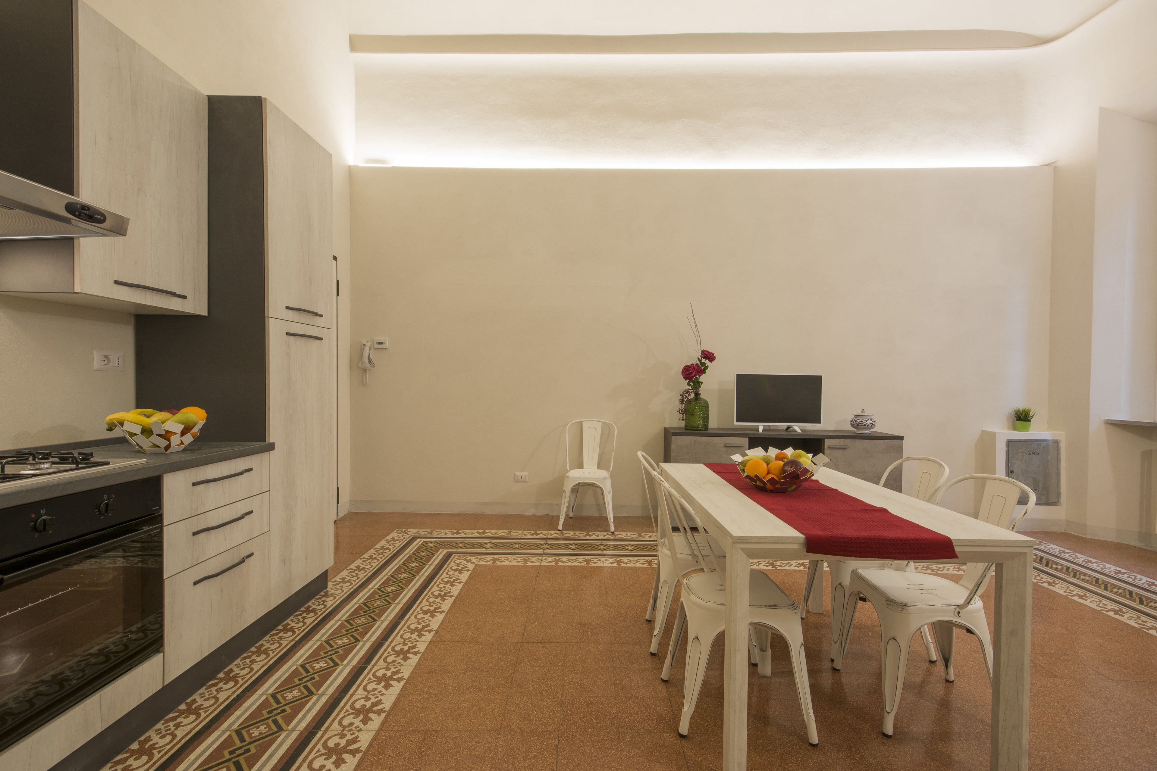 A modern kitchen with white cabinets, a stove, and a dining area with a table and chairs.