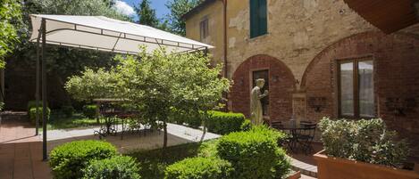 Un cortile con un'area salotto coperta, una statua e un edificio con finestre ad arco.