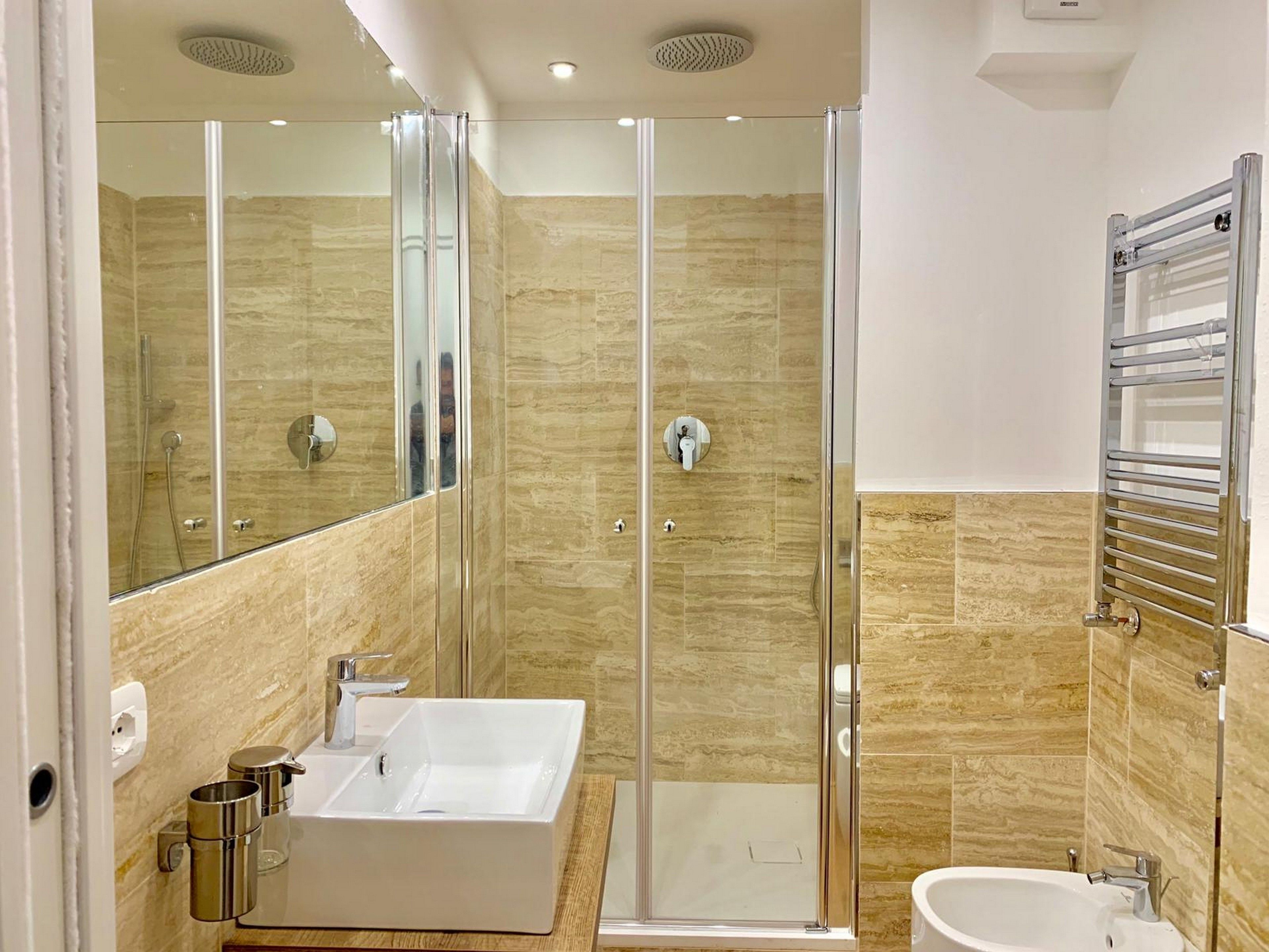 Une salle de bain moderne dotée d’une douche à parois de verre, d’une baignoire sur pieds et d’un lavabo séparé.