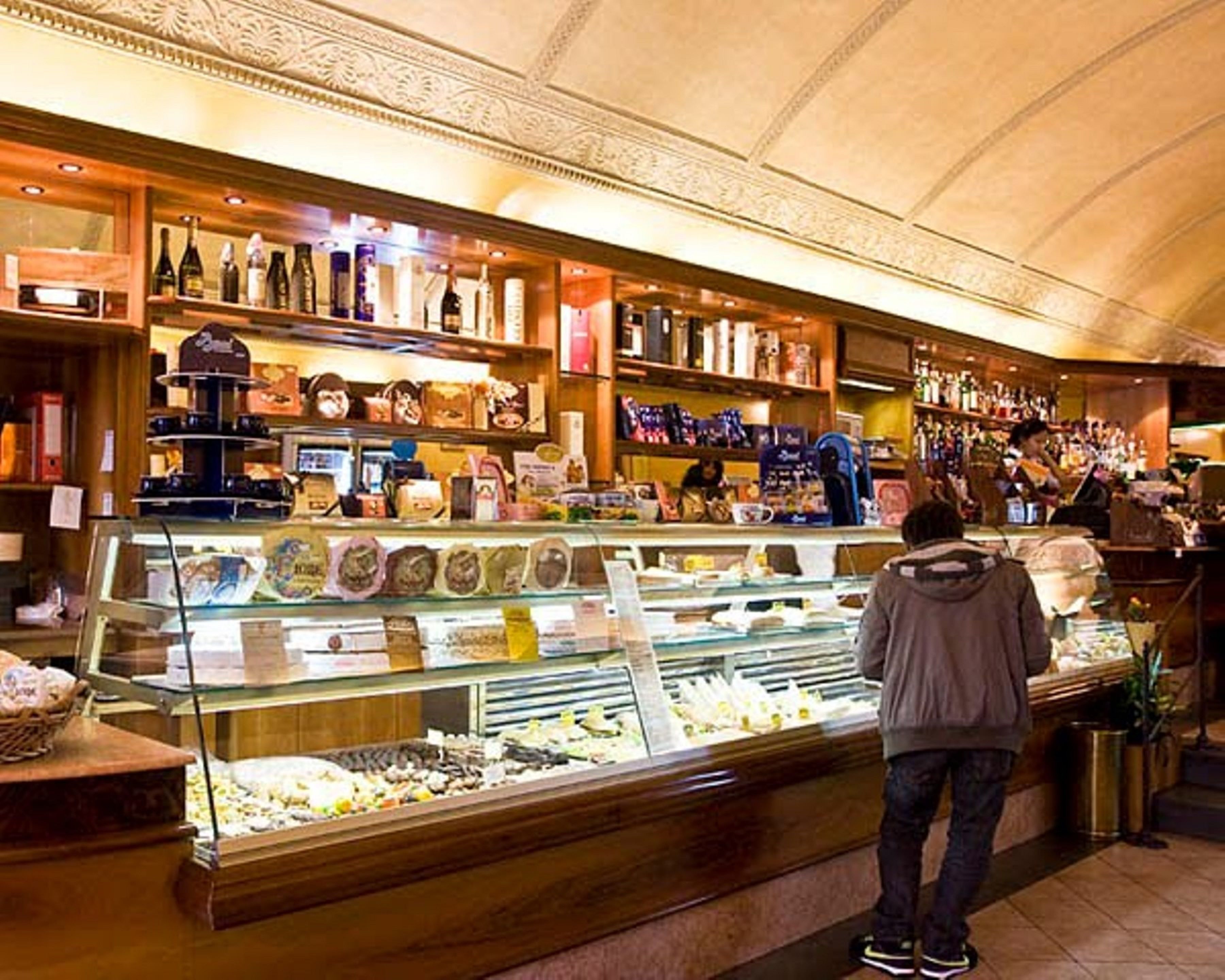 A bakery display with various baked goods and a person standing in front of it.