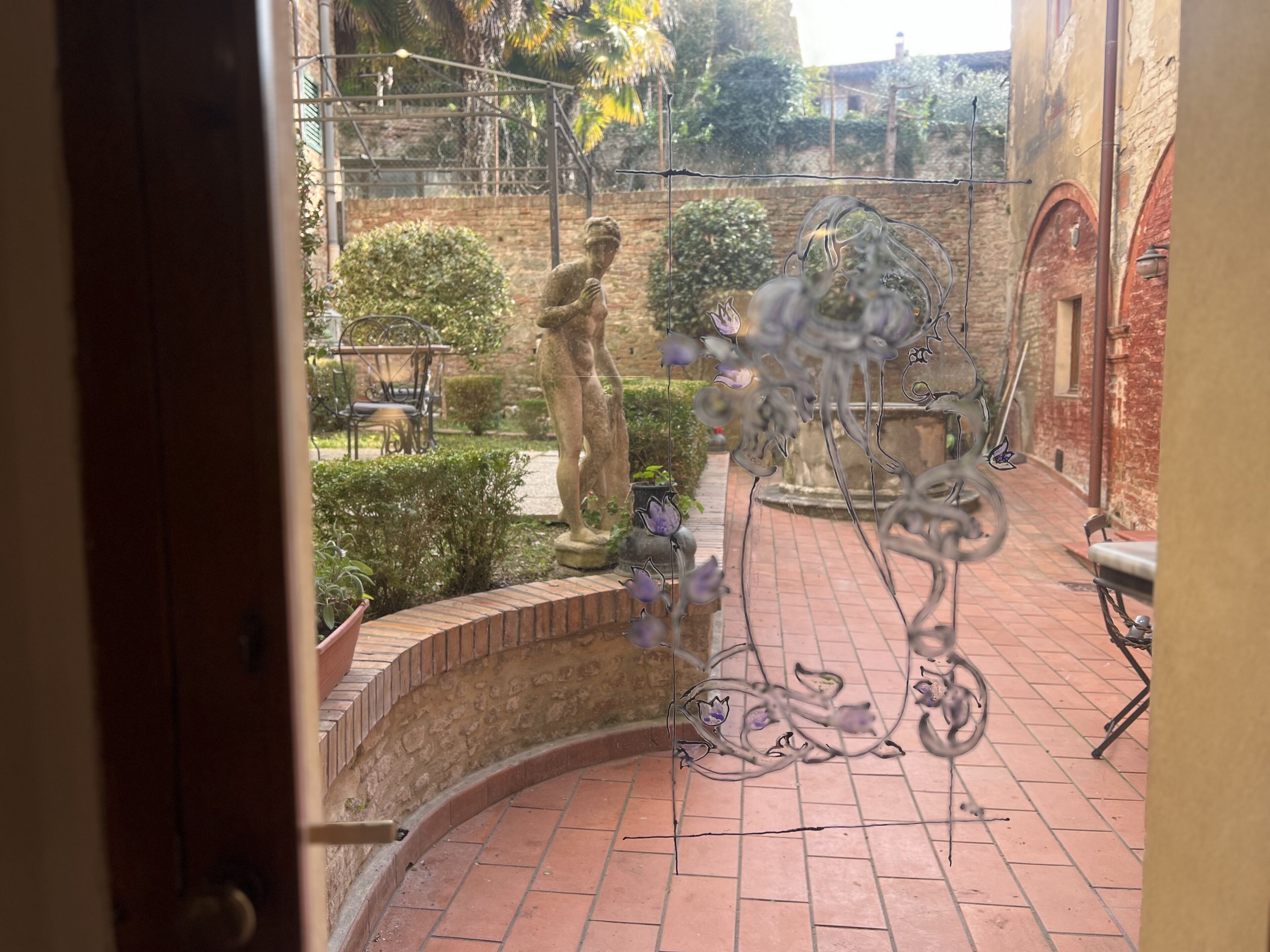 A courtyard with a statue, a fountain, and a brick wall.