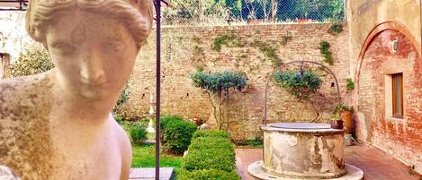 Une cour avec une statue, une fontaine et un mur en briques.