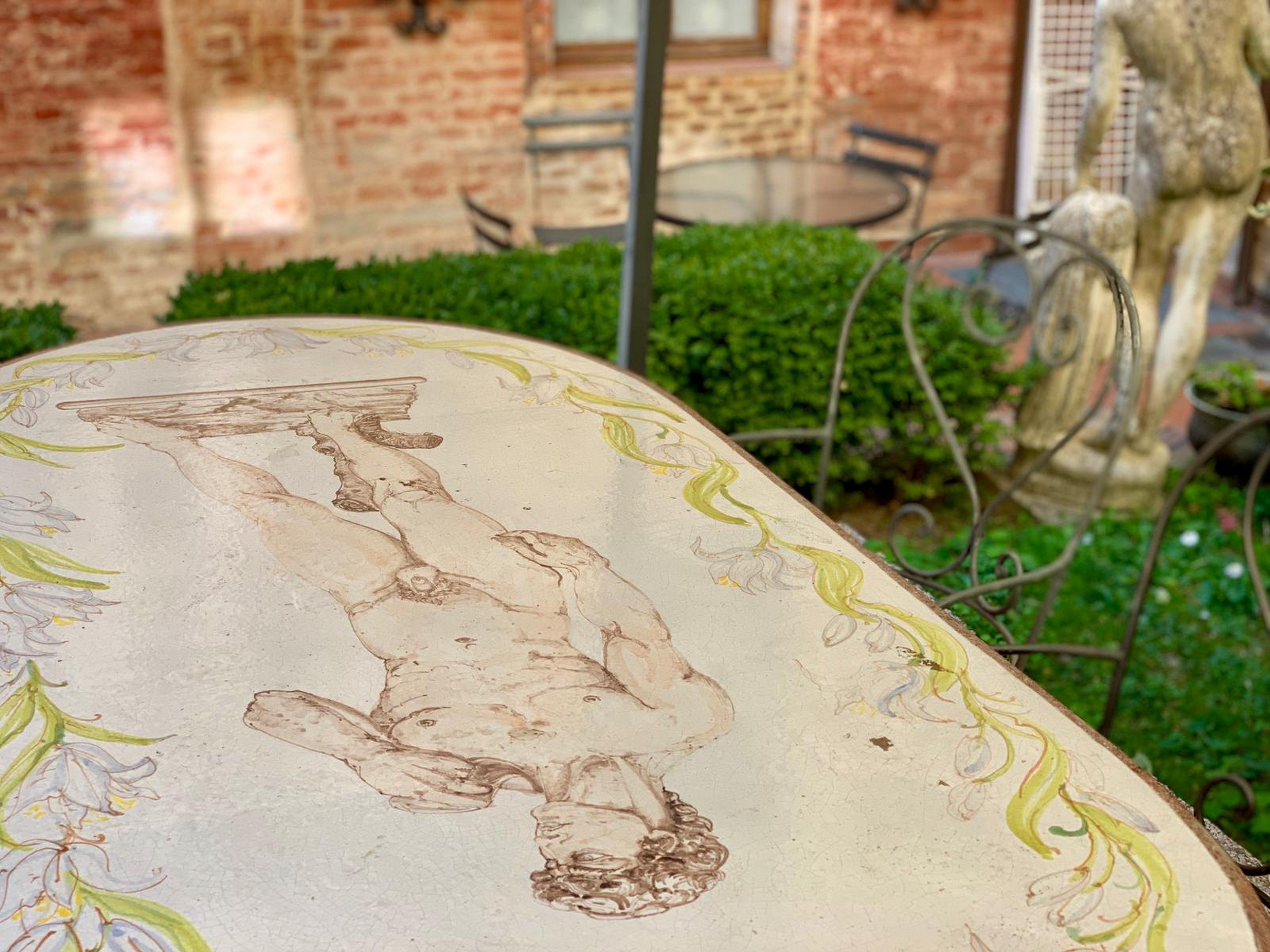 A table with a detailed etching of a mythical creature, surrounded by greenery and a brick wall.
