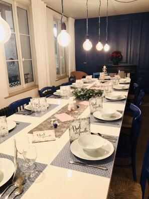 Une longue table à manger, dressée pour un repas de famille, avec des marque-places indiquant « Noël en famille ».