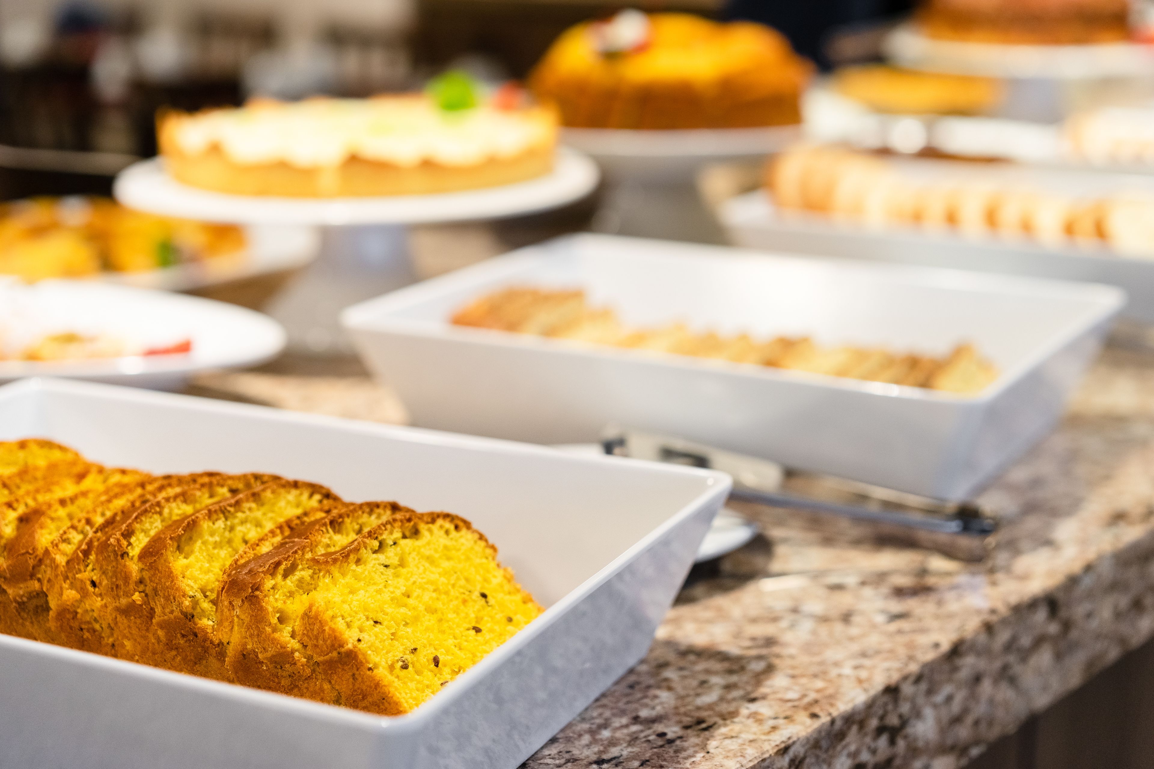 A buffet with various baked goods, including a loaf of bread and several cakes.