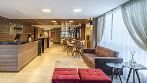 A hotel lobby with a reception desk, seating area, and a bar. - Hotel Fioreze Primo (Gramado)