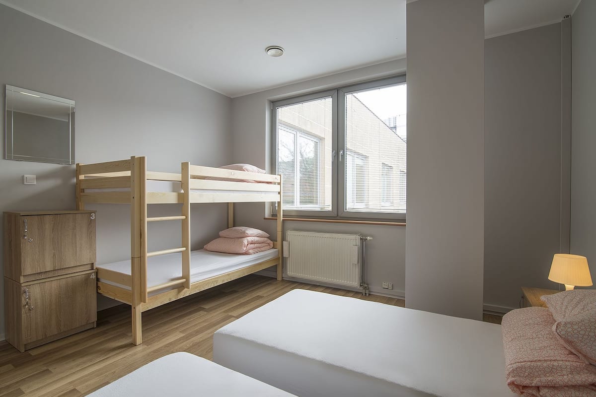 Quarto com beliche, janela, radiador e abajur.