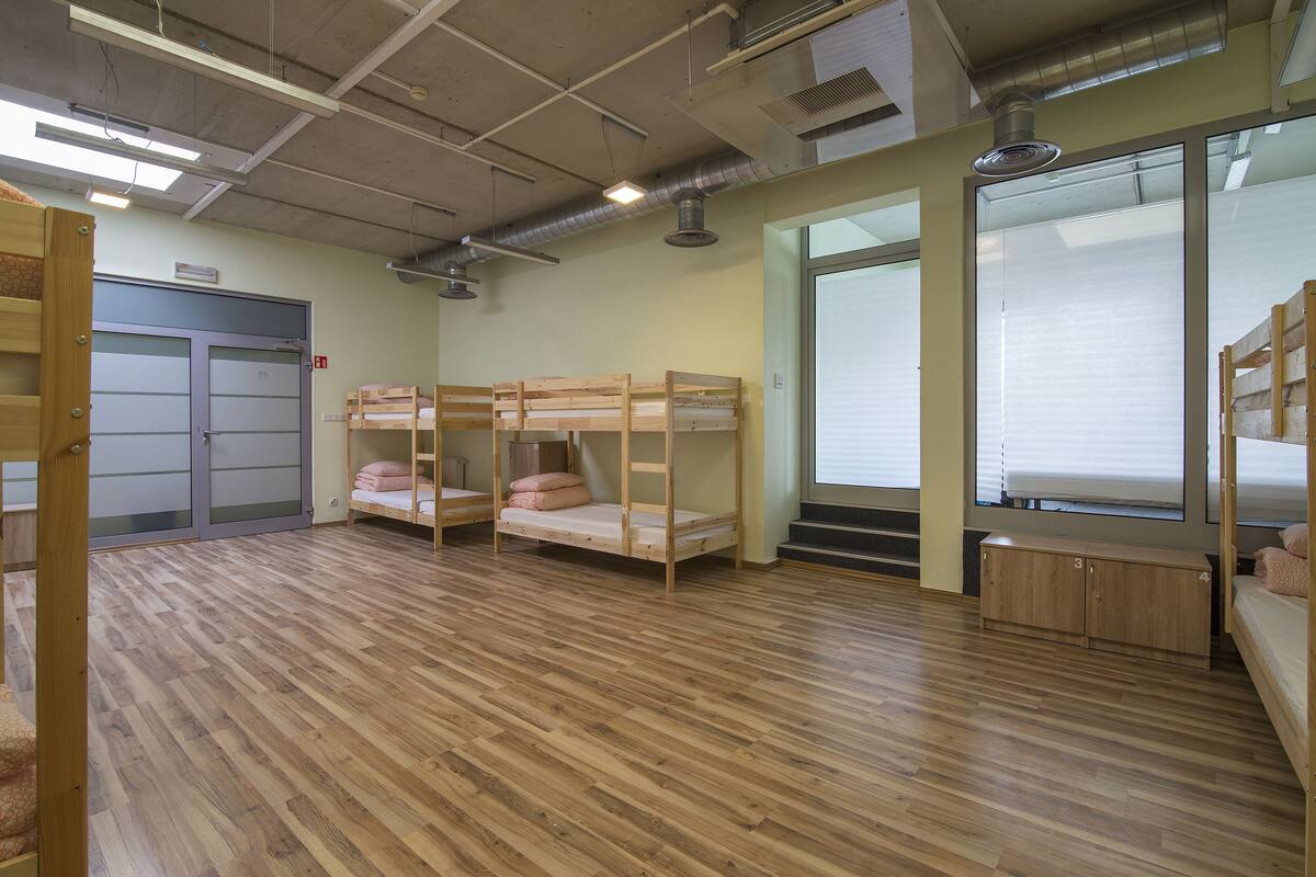 Quarto com beliches, piso de madeira e uma janela grande.