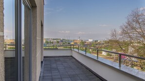 Un balcon doté d’un sol carrelé et d’une rambarde en métal.