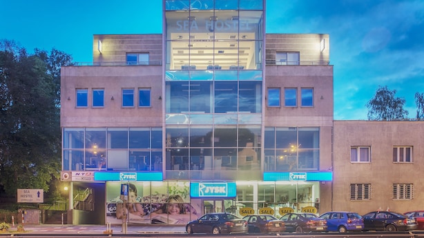 Un bâtiment moderne à la façade vitrée, sur lequel on peut lire les inscriptions « SEA HOSTEL » et « RYJSK ».