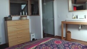 A bedroom with a wooden dresser, a bed with a patterned bedspread, a mirror above the dresser, and a small stool. - 220 m² house, sleeps 8–10. With private grounds and a terrace overlooking the lake and spa (Hautecour)