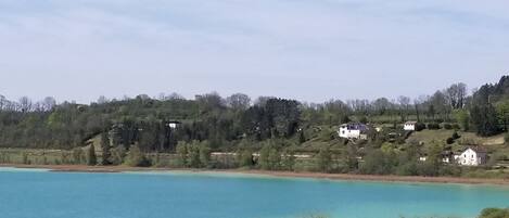 Ein See mit Häusern am Ufer und ein Gebäude mit geneigtem Dach im Vordergrund.