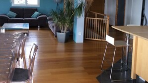 A modern living room with a sofa, a coffee table, and a dining area with chairs and a table. - 220 m² house, sleeps 8–10. With private grounds and a terrace overlooking the lake and spa (Hautecour)