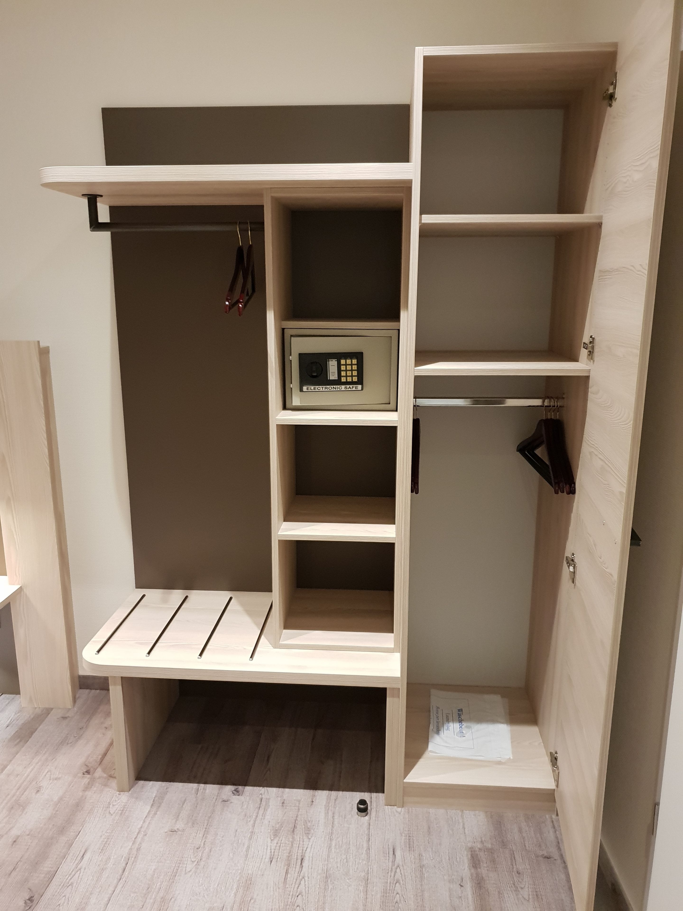 Un meuble de rangement en bois doté de plusieurs étagères et compartiments, dont un coffre-fort verrouillable.