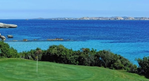 Ein Küsten-Golfplatz mit freiem Blick auf das Meer und weit entfernte Felsenformationen.