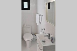 Een moderne badkamer met toilet, wastafel en spiegel.