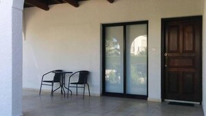 A covered patio with two chairs and a door. - Royal Sunset Studios (Limassol)