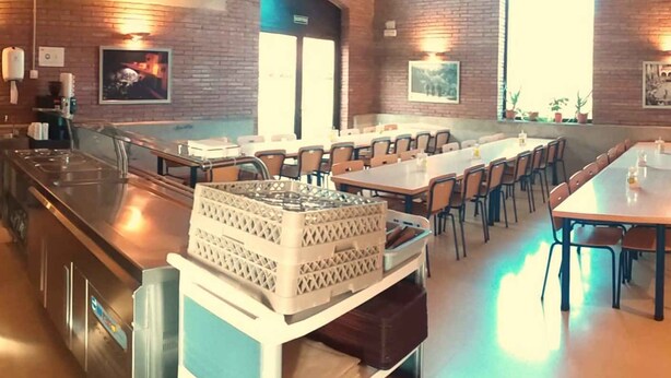 A spacious restaurant with brick walls, multiple dining tables, and chairs. - Alberg Rural Ruta del Ferro (Sant Joan de Les Abadesses)