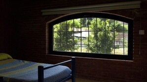 A room with a bed, a large arched window, and brick walls. - Alberg Rural Ruta del Ferro (Sant Joan de Les Abadesses)