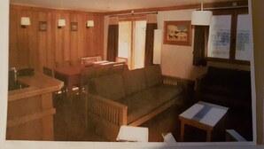 Una habitación con interior de madera, un sofá, una mesita y una ventana con vistas.