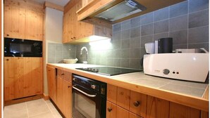 Una cocina con armarios de madera, microondas, estufa, lavavajillas y cafetera.