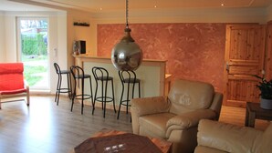 A modern living room with a leather sofa, a wooden coffee table, and a bar area with stools.