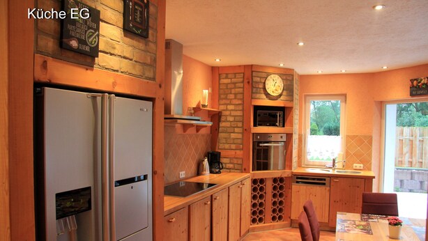 A kitchen with wooden cabinets, a refrigerator, a coffee maker, and a clock on the wall.