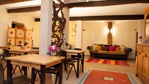 A dining area with wooden tables and chairs, a sofa, and a cabinet. - Vila dos Castanheiros (Ferreira do Zezere)