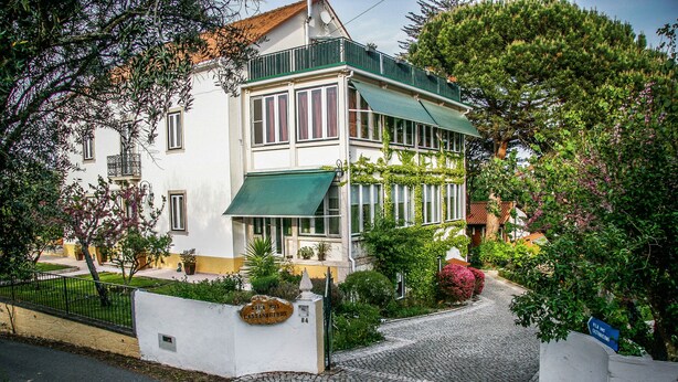 A two-story building with a green awning, a white facade, and a cobblestone entrance. - Vila dos Castanheiros (Ferreira do Zezere)