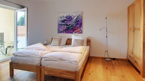 A modern bedroom with a wooden bed, a large window, and a floor lamp.