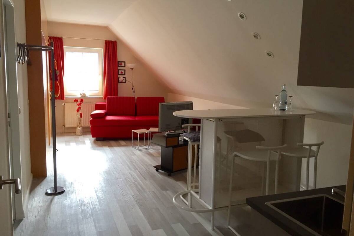 A compact living space with a kitchenette, a dining area, and a red sofa.