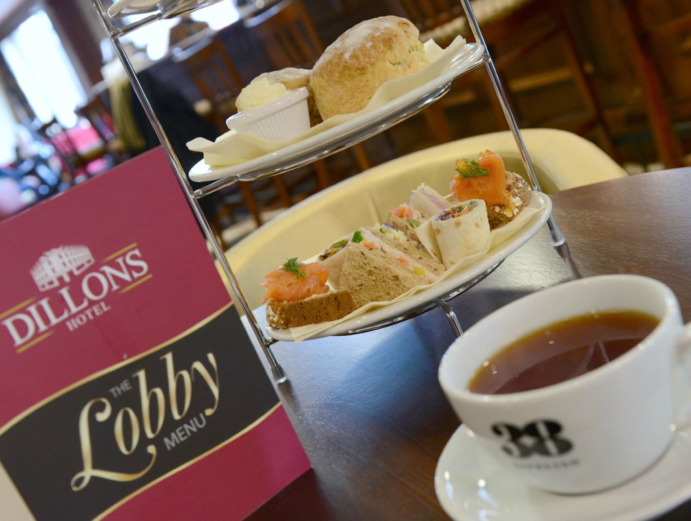 Een etagère met gebak en een kop thee, samen met een menu van The Dillons Hotel.