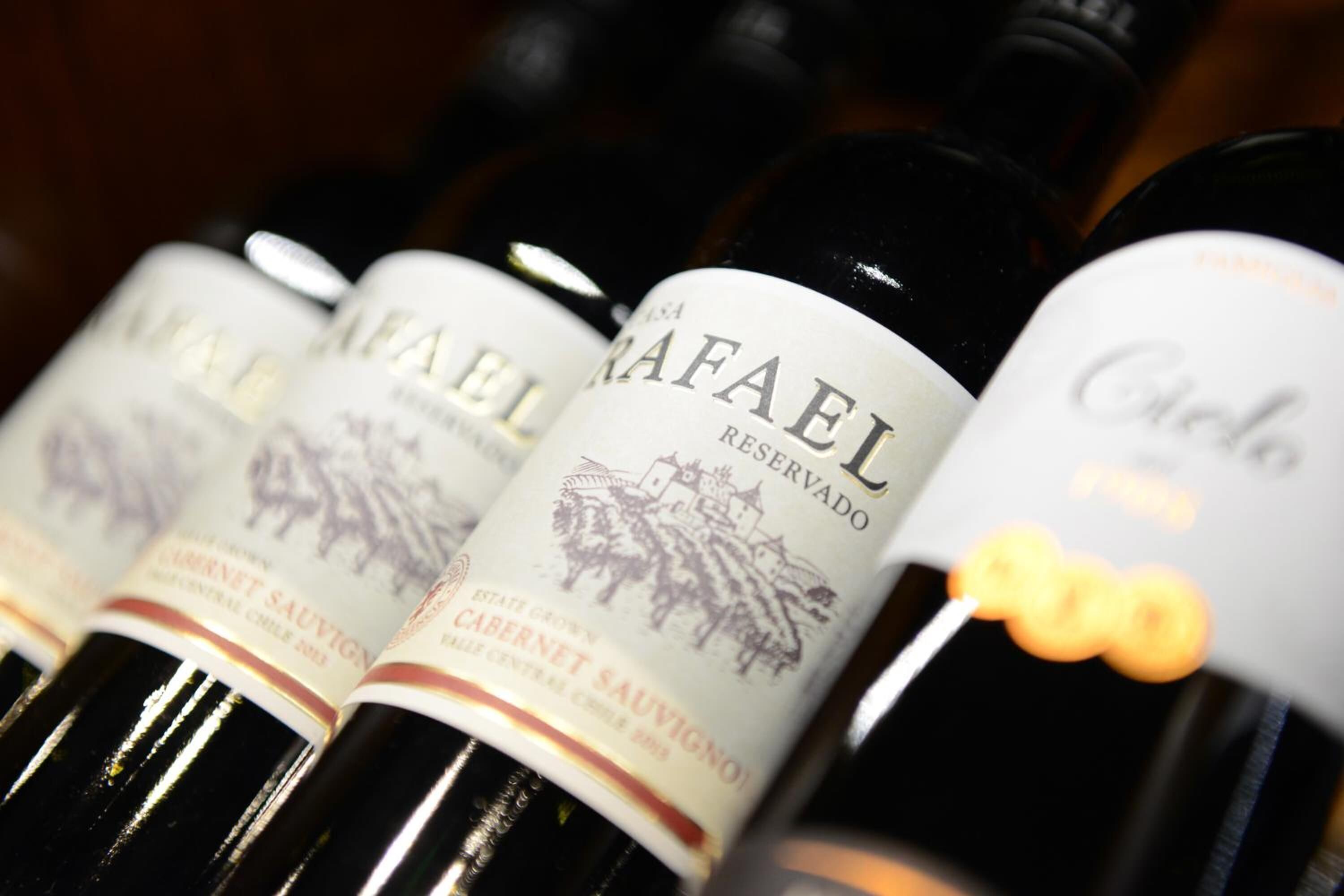 A row of wine bottles with labels, including one labeled "Rafael Reserva."