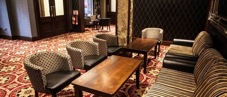 A lobby with patterned carpet, a wooden coffee table, patterned chairs, and a striped sofa.