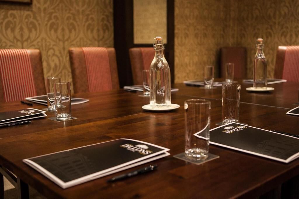 Un salón de conferencias con una mesa de madera, botellas de vidrio transparente y tarjetas de nombre.