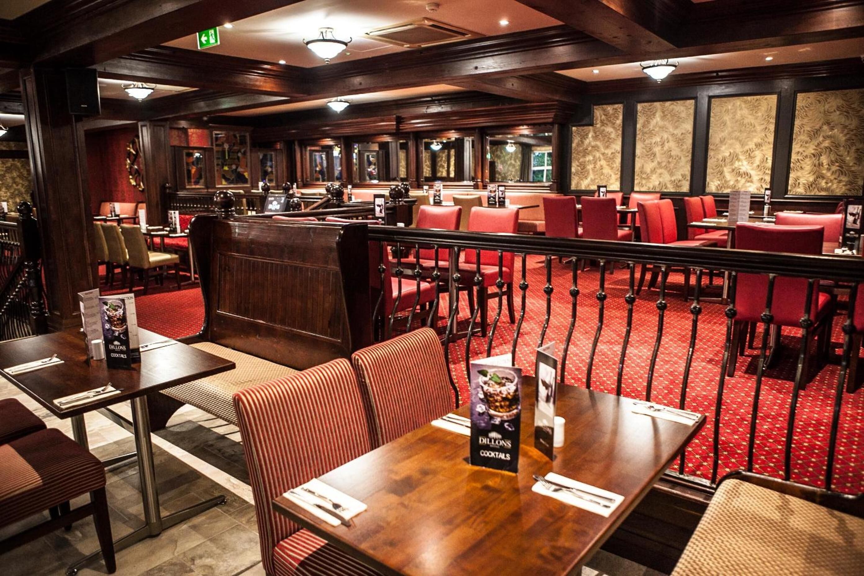 A restaurant with a bar area, red upholstered booths, and a red carpeted floor.