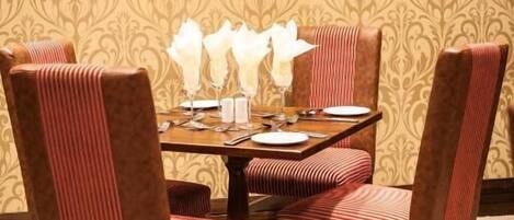 A dining area with a table set for four, surrounded by upholstered chairs with a striped pattern.