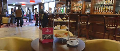 Un vestíbulo con una zona de bar, una mesa de buffet con una caja que dice 'Dillon's Lobby Buffet' y una taza de café sobre una mesa.