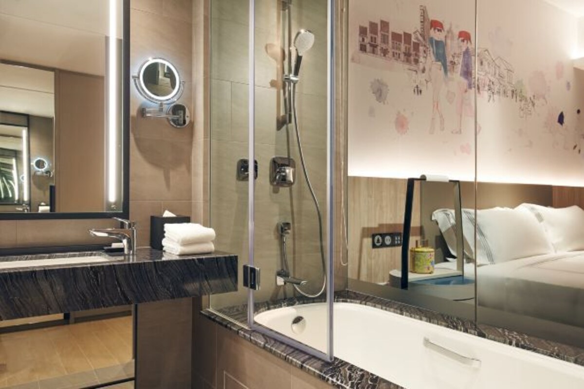 A modern bathroom with a glass-enclosed shower, a large mirror, and a bathtub.