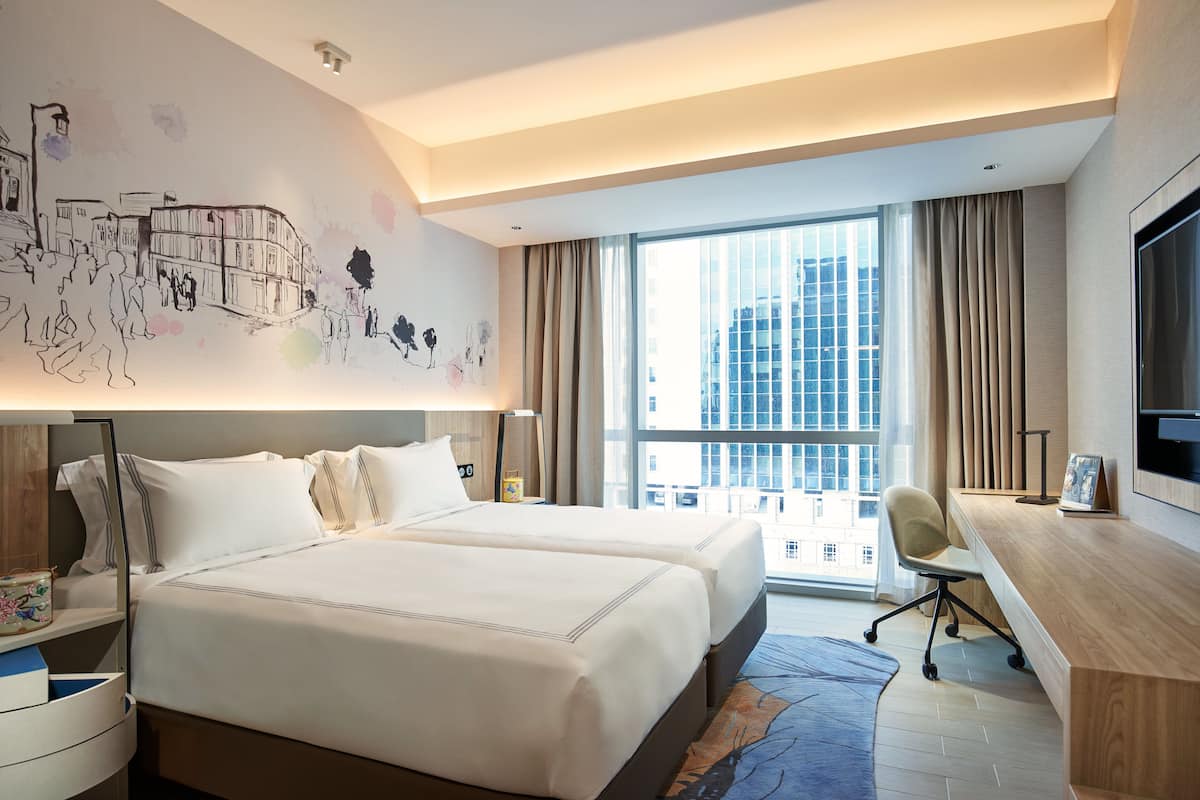 Une chambre d’hôtel avec un grand lit, un bureau et une fresque représentant un paysage urbain sur le mur.