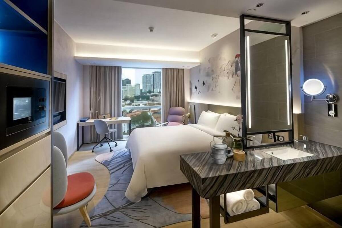 Une chambre d’hôtel équipée d’un lit, d’un bureau, d’une chaise, d’une télévision, d’une salle de bain et offrant une vue sur la ville.