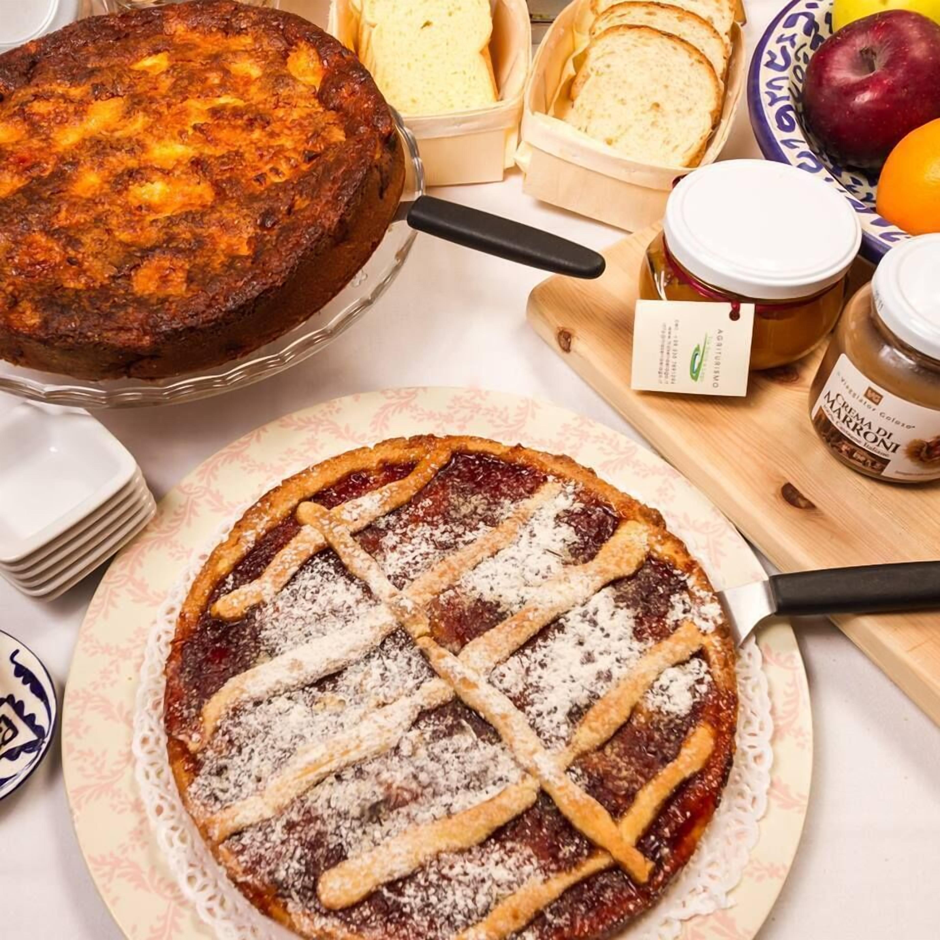 A dessert table with a cake, a pie, bread, and jars of preserves.