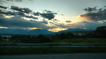 Un coucher de soleil sur des montagnes, avec une route au premier plan.